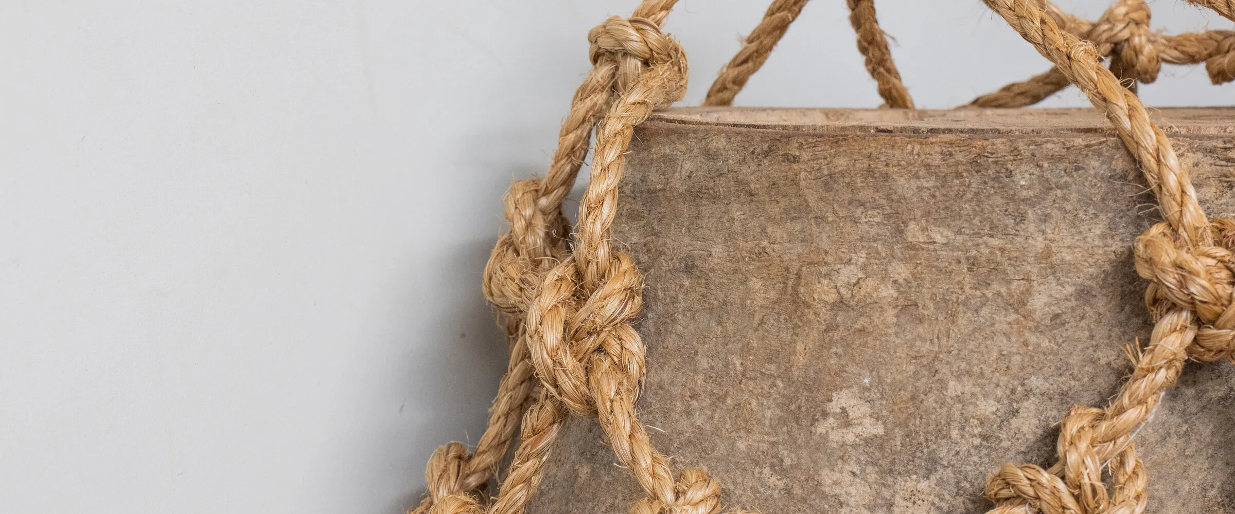 A close view of the manilla rope net drawn tight around a piece of timber.