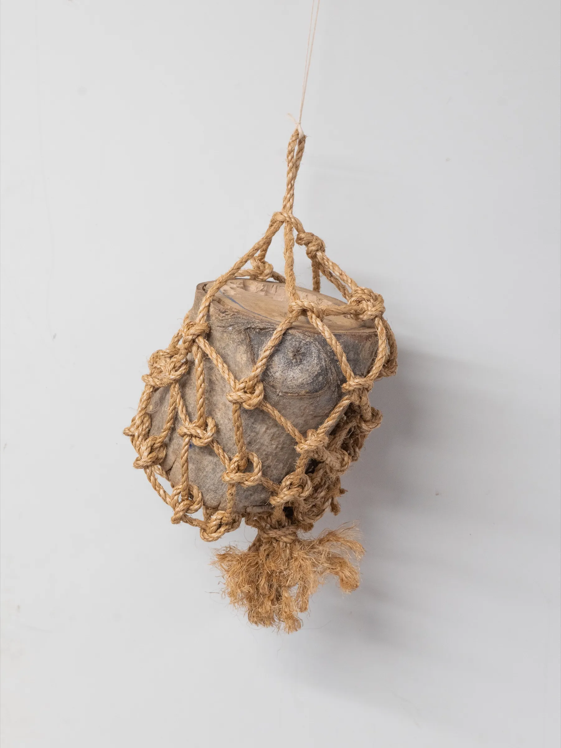 The rope cradle tightened around a rounded piece of wood.