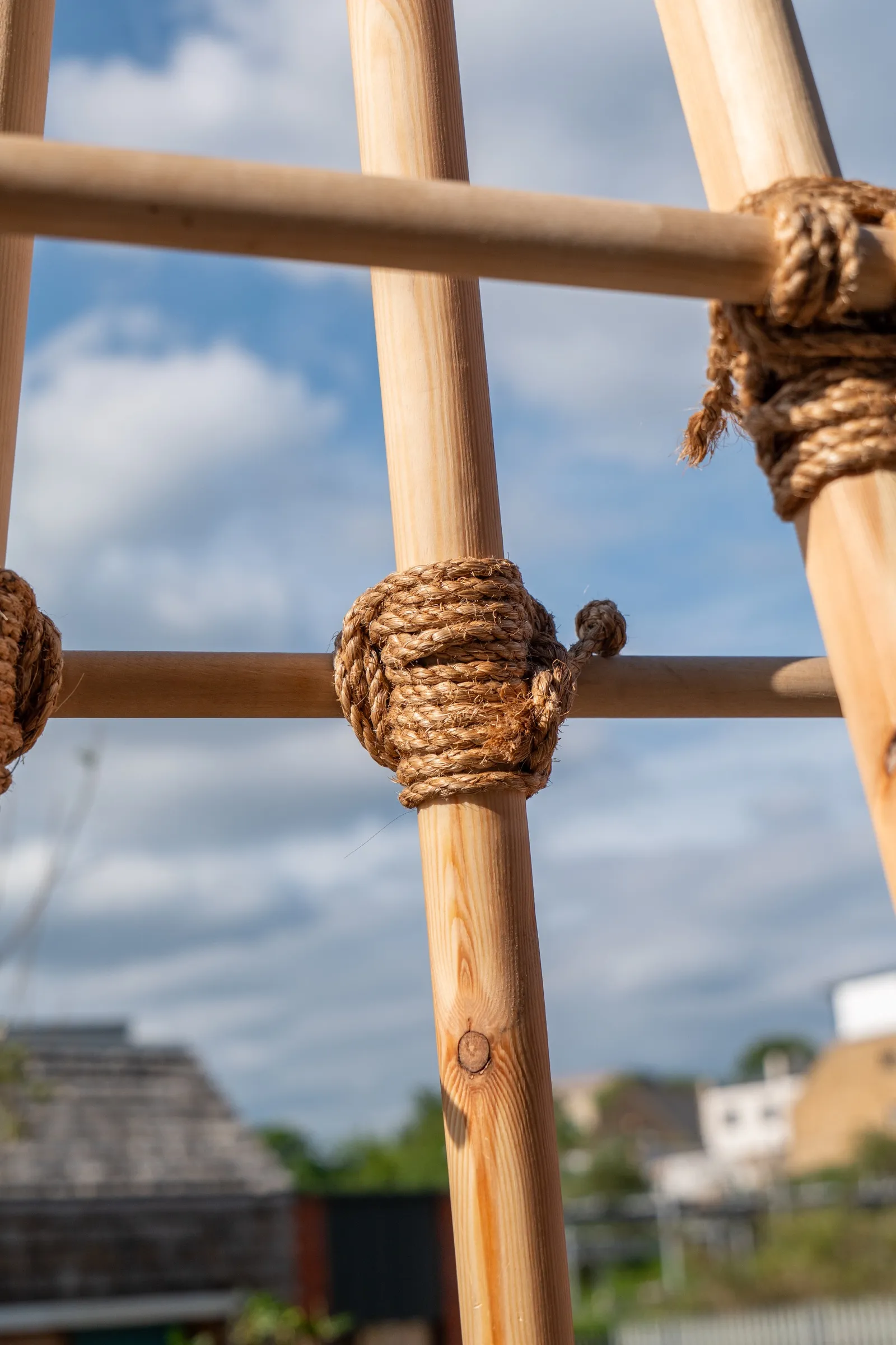 A close view of manilla rope binding the tower's rounded timber poles against the sky.